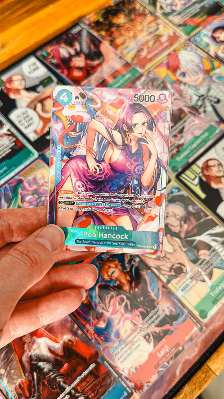 A collector holding an alt-art One Piece card over a table of cards